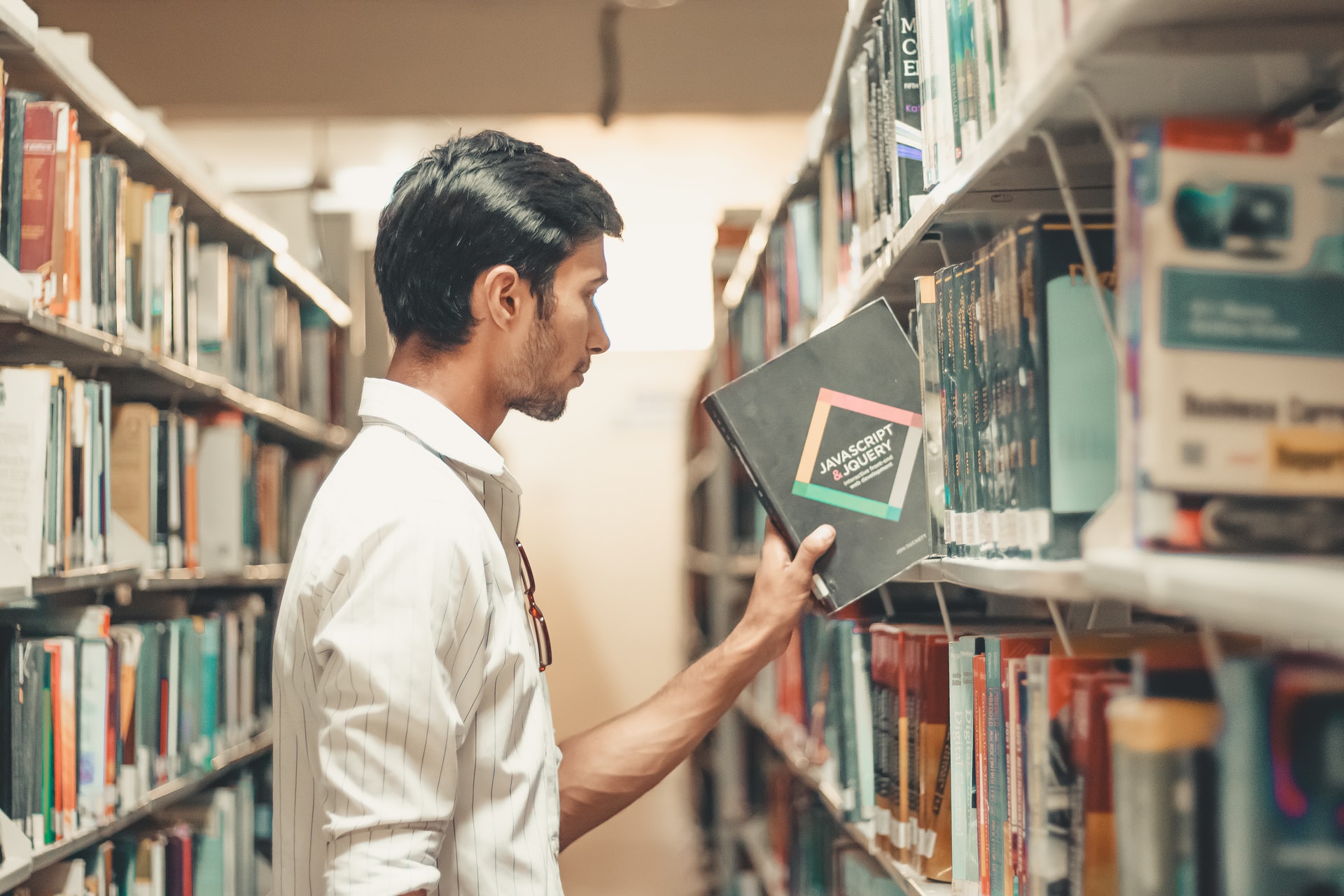 Pessoa escolhendo um livro em uma biblioteca